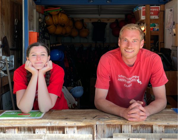Zwei Mitarbeiter stehen im Empfangsraum und l�cheln in die Kamera