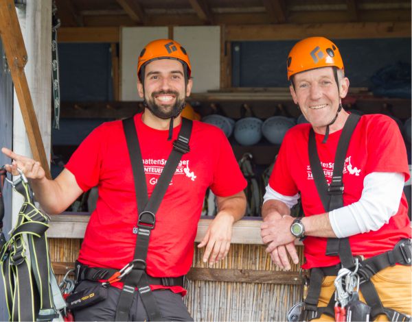 Zwei Mitarbeiter des Kletterparks stehen am Empfangstresen und l�cheln in die Kamera