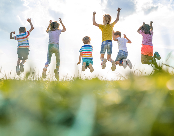 Aufnahme von hinten sechs Kinder springen gleichzeitig in die H�he 