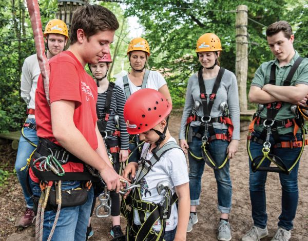 Ein Mitarbeiter pr�ft den Sitz der Kletterausr�stung bei einem Kind
